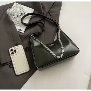 Close-up of deep green underarm bag featuring glossy texture and silver chain strap