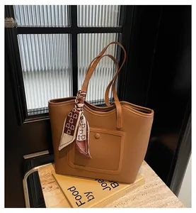 Detailed shot of brown pebble leather tote bag featuring buckle pocket and bear print scarf