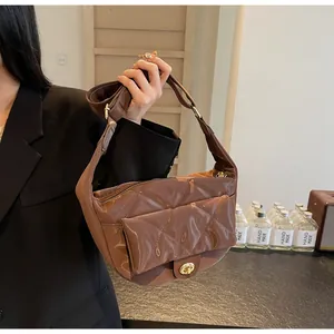 Detail of a brown quilted leather saddle bag showing the glossy finish and gold twist lock