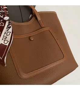 Macro shot of brown lychee leather tote bag featuring a decorative patterned silk scarf