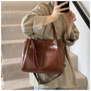 Dettaglio di una borsa tote in pelle marrone con ciondolo a racchetta e fascino