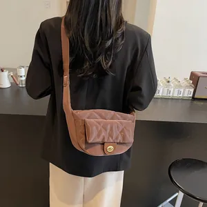 Minimalist brown quilted leather crossbody saddle bag with adjustable strap worn by model