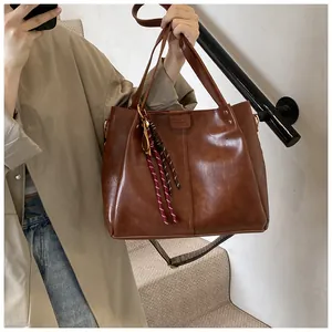 Dettaglio della borsa tote marrone caramello con trama in pelle vintage e ciondolo