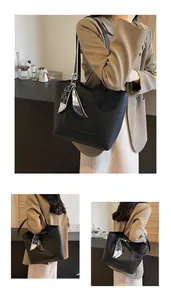 Detail of black litchi grain leather tote bag with printed silk scarf on handle