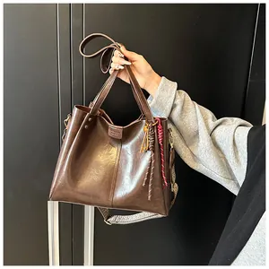 Dettaglio della borsa tote vintage in pelle marrone con tracolla larga e ciondoli