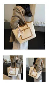 Detail of a large cream tote bag with brown straps and a decorative floral bear scarf