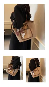 Detail of beige tote bag with brown trim, front pocket, and elegant floral scarf accent
