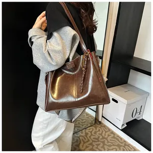 Dettaglio della borsa tote in pelle marrone scuro lucida con ciondolo intrecciato