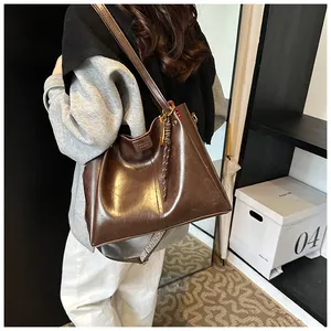 Dettaglio borsa tote vintage in pelle marrone con tracolla larga e targhetta
