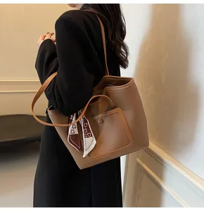 Detail of tan pebble leather tote bag with decorative scarf and buckle pocket