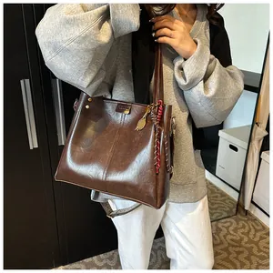 Dettaglio borsa shopper marrone scuro con ciondolo a racchetta da tennis e logo in metallo