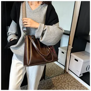 Dettaglio della borsa tote in pelle marrone scuro con ampia tracolla a motivi geometrici