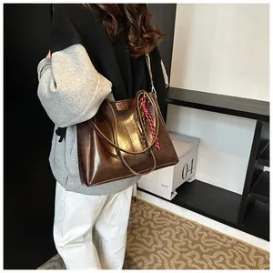 Dettaglio della borsa tote in pelle marrone scuro con tracolla larga e ciondolo