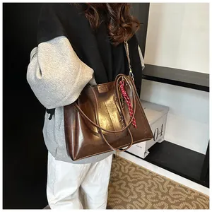 Dettaglio borsa tote vintage in pelle marrone con sciarpa a righe e targhetta moda