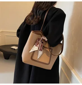 Detail of khaki and brown tote bag with printed silk scarf on a model in a black coat