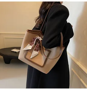 Detail view of large beige pebble leather tote with brown trim and floral scarf accent