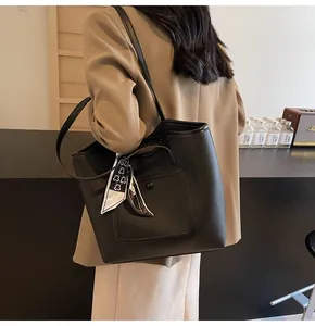 Detail of a black pebbled leather tote bag with a chic decorative silk scarf on the handle