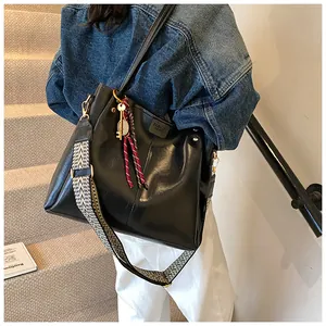 Dettaglio borsa tote nera con tracolla geometrica indossata da modella sulle scale