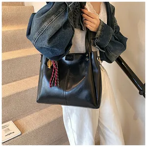 Dettaglio della borsa tote nera retrò con pendente dorato e nappa a righe decorativa