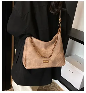 Detail view of retro brown faux suede tote bag with metallic fashion plaque and chain