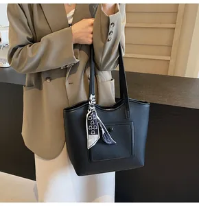 Detailed view of black litchi leather tote bag with printed silk scarf on handle