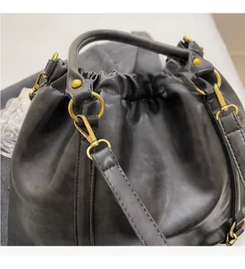 Close-up of black pleated PU leather bag with glossy finish and gold metal hardware