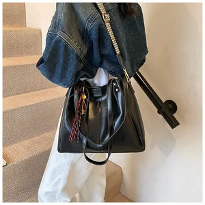 Dettaglio borsa tote nera con tracolla larga intrecciata decorativa e finiture dorate