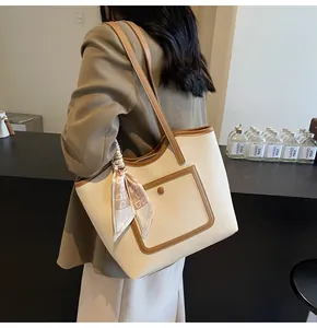 Detail of off-white lychee leather tote bag with brown trim and bear print silk scarf