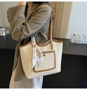 Detail of large tote bag in cream faux leather with brown trim and bear scarf