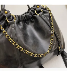 Detail of soft black PU leather texture with elegant gold chain and metallic buckle