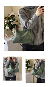 Detail of dark green suede hobo bag with gold chain strap and fashion metal logo
