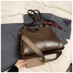 Dettaglio della grande borsa tote marrone con tracolla larga in tessuto e foulard