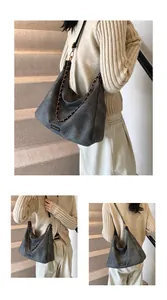 Detail of dark grey faux suede hobo bag featuring chain strap and fashion label detail