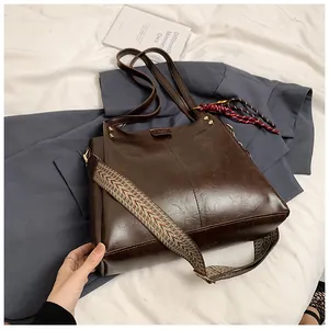 Dettaglio borsa shopper marrone scuro con tracolla geometrica intrecciata e finiture dorate lucide