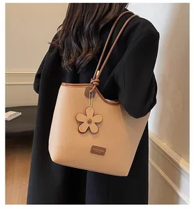 Detail of apricot bucket bag with lychee texture leather and flower charm accessory