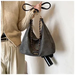 Detail of dark gray faux suede hobo bag with gold metal chain and Fashion label decoration
