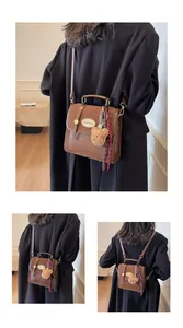 Détails d'un sac à main vintage en cuir marron avec breloque ours et ruban à carreaux élégant