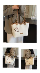 Detail of off-white bucket bag with brown trim and floral charm in a lifestyle setting