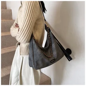 Macro shot of dark grey vintage faux suede tote bag with elegant gold chain and fashion label