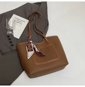Detail of a brown leather tote bag with silk scarf and front snap pocket for daily use