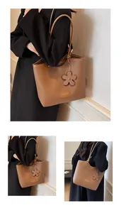 Detail of brown litchi leather bucket bag with flower charm and logo plate on straps