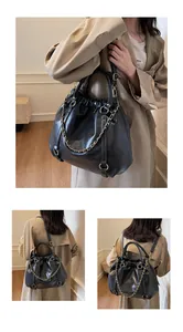 Detail of black pleated bucket bag with gold chain and adjustable shoulder strap