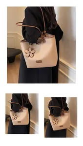 Detail view of stylish apricot leather bucket bag with brown trim and floral charm