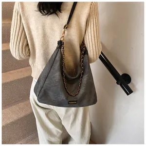 Detailed view of grey faux suede crossbody bag with gold chain and fashion label detail