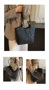 Detail of black pebbled leather bucket bag with gold hardware and flower charm
