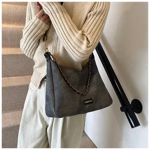 Detail of dark gray faux suede tote bag with metal chain strap and fashion label
