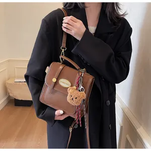 Sac à bandoulière marron en cuir avec ours en peluche et plaque dorée sur modèle
