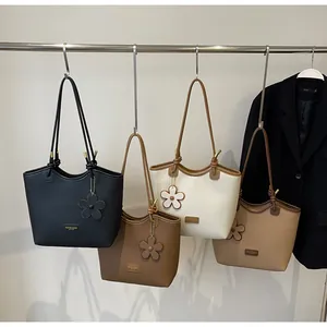 Close-up of four minimalist leather bucket bags in neutral tones with flower charms