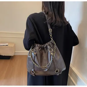 Close-up of vintage dark brown pleated PU leather tote bag with elegant gold chain strap