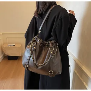 Detail of vintage brown pleated faux leather bag with gold rings and metal chain strap